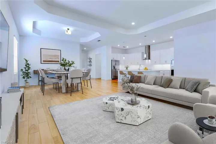 Living room featuring a raised ceiling, light wood-style floors, and recessed lighting