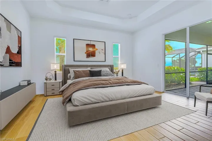 Bedroom featuring light wood-style floors, a raised ceiling, and access to exterior