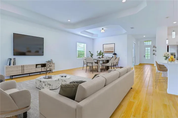 Living room featuring a raised ceiling, light wood finished floors, plenty of natural light, and recessed lighting