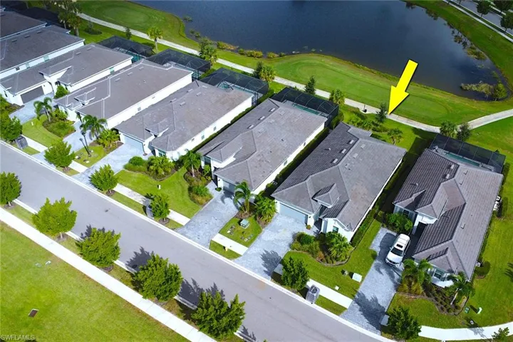 Aerial perspective of suburban area featuring a nearby body of water and a golf course