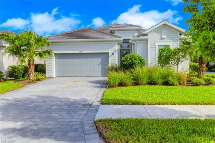 View of front of home with decorative driveway, a garage, stucco siding, and a front yard