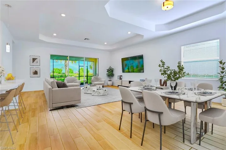 Dining room with a tray ceiling, recessed lighting, and light wood-type flooring