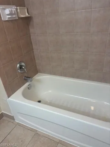 Full bath featuring tile patterned floors, baseboards, and shower / tub combination