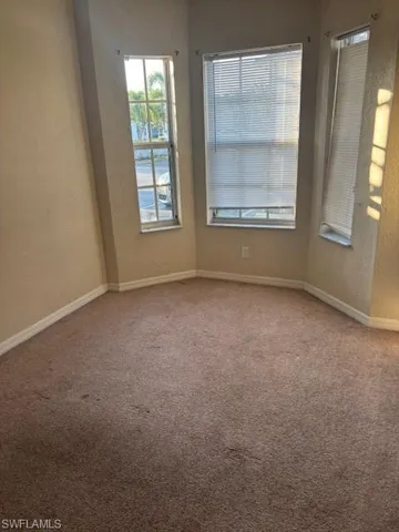 Carpeted empty room featuring a textured wall and baseboards