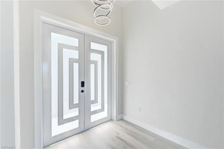 Foyer entrance with french doors, wood finished floors, and a chandelier