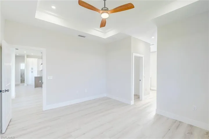 Primary room with recessed lighting, a tray ceiling, light wood finished floors, and a ceiling fan