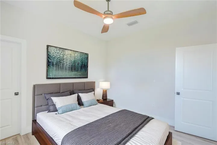 Bedroom with light wood-style flooring and a ceiling fan. Virtual Staged