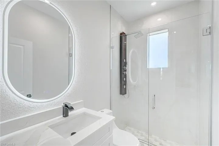 Bathroom featuring a textured wall, a stall shower, and vanity