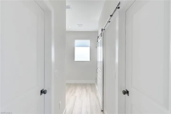 Hall with a barn door and light wood-type flooring