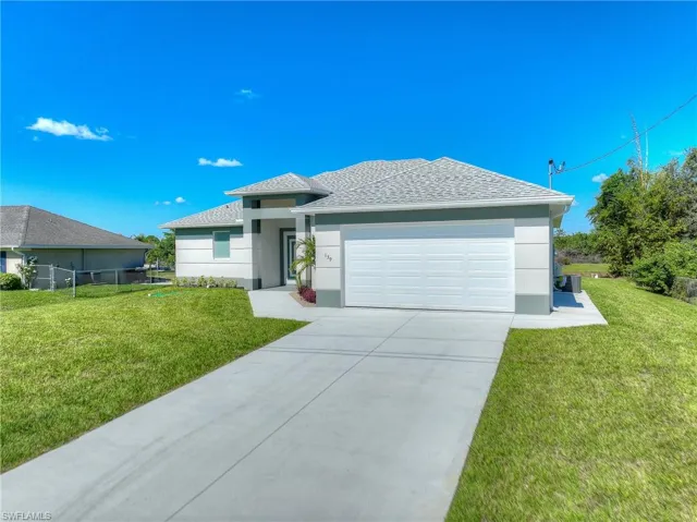 View of front of property with a front yard, concrete driveway, roof with shingles, an attached garage, and stucco siding