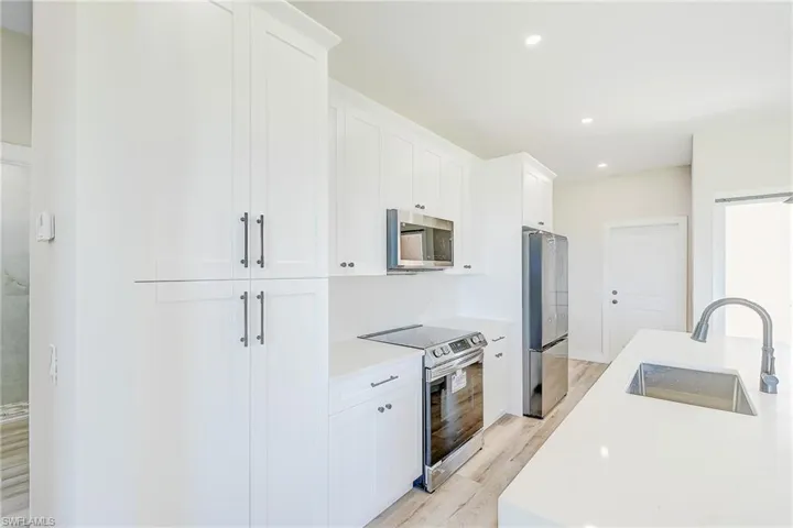 Kitchen featuring appliances with stainless steel finishes, light wood-style floors, white cabinetry, and recessed lighting