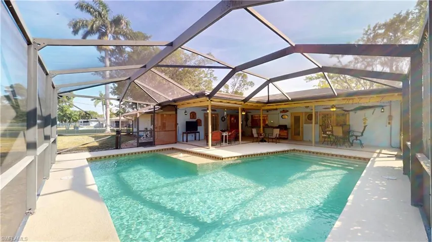 Swimming pool with a sunroom, a patio area, and glass enclosure