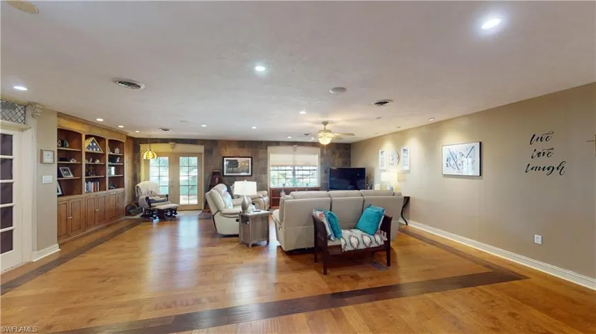 Living room with french doors, light wood-style floors, recessed lighting, built in shelves, and ceiling fan