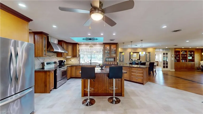 Kitchen featuring appliances with stainless steel finishes, brown cabinets, a kitchen breakfast bar, and recessed lighting