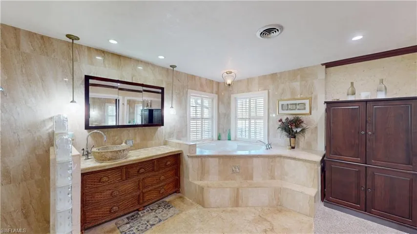 Full bath with vanity, a garden tub, recessed lighting, and tile walls