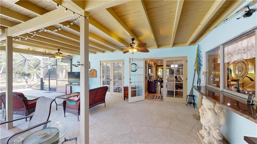 Sunroom / solarium featuring a ceiling fan, a patio, french doors, and beamed ceiling