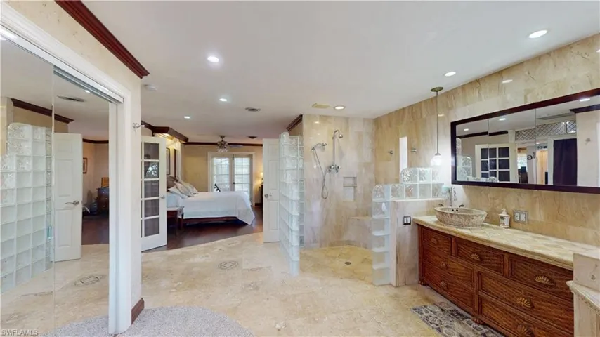 Ensuite bathroom featuring walk in shower, french doors, recessed lighting, vanity, and ornamental molding