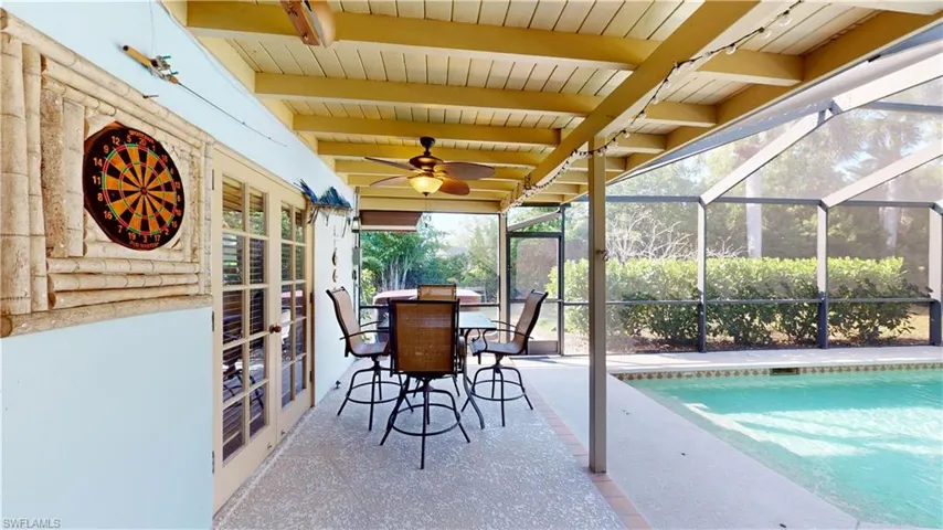 View of patio with glass enclosure, a sunroom, a ceiling fan, an outdoor pool, and outdoor dining space