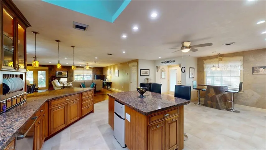 Kitchen with pendant lighting, brown cabinetry, a ceiling fan, dark stone counters, and recessed lighting