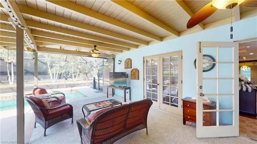 Sunroom featuring a ceiling fan, beamed ceiling, and a patio