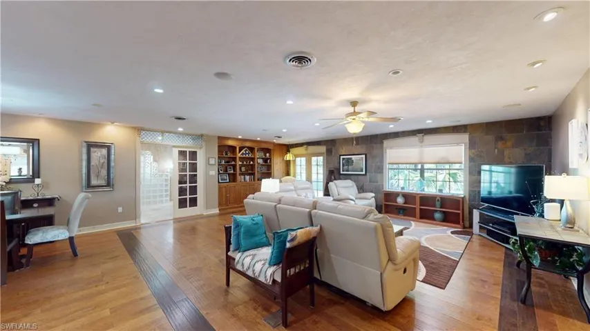 Living room with light wood-style flooring, ceiling fan, recessed lighting, and built in shelves