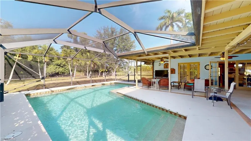 Outdoor pool featuring a patio, french doors, glass enclosure, and a sunroom