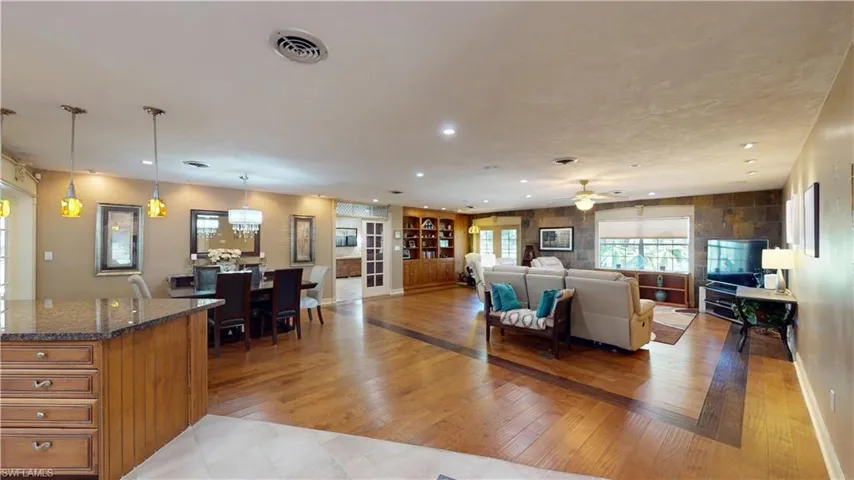 Living area with light wood-style floors, built in shelves, recessed lighting, and a ceiling fan