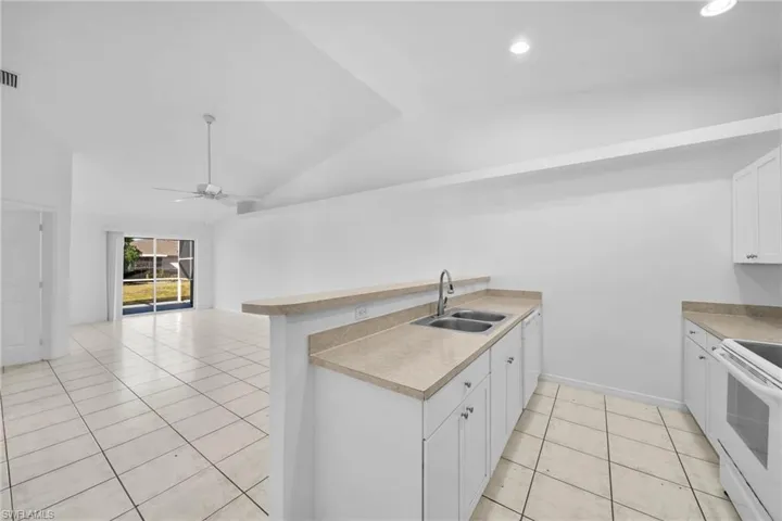 Kitchen features white cabinetry, a dual basin stainless steel sink, and light-toned countertops