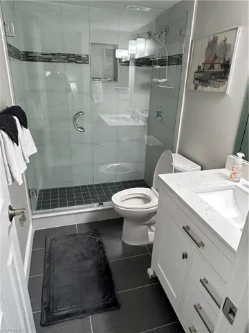 Bathroom with tile patterned flooring, vanity, toilet, and walk in shower