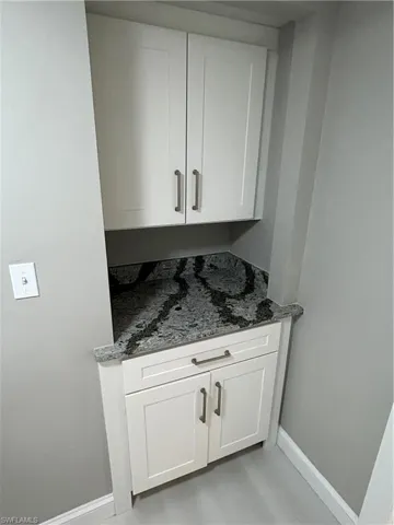 Bar with white cabinets and dark stone counters