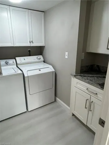 Laundry room featuring separate washer and dryer and cabinets