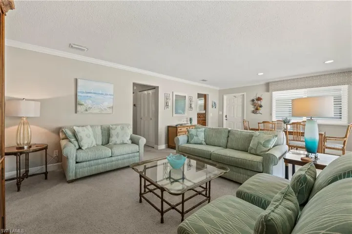 Carpeted living area with crown molding, a textured ceiling, and recessed lighting