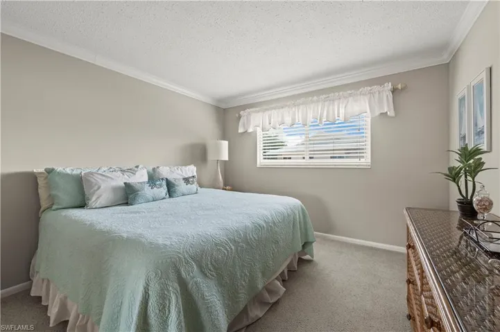 Bedroom with ornamental molding, a textured ceiling, and carpet floors