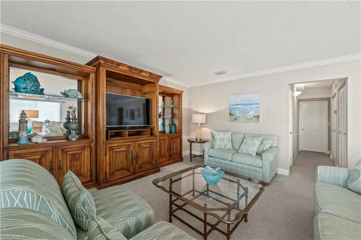 Living room with attic access, light colored carpet, crown molding, and a textured ceiling