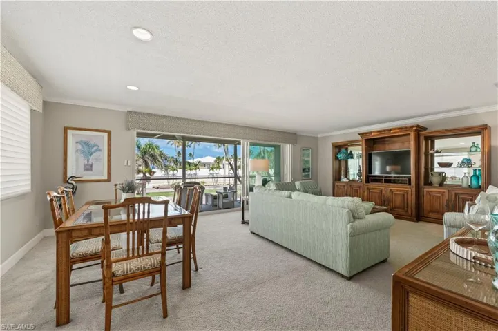 Living room featuring light colored carpet, ornamental molding, a textured ceiling, and recessed lighting