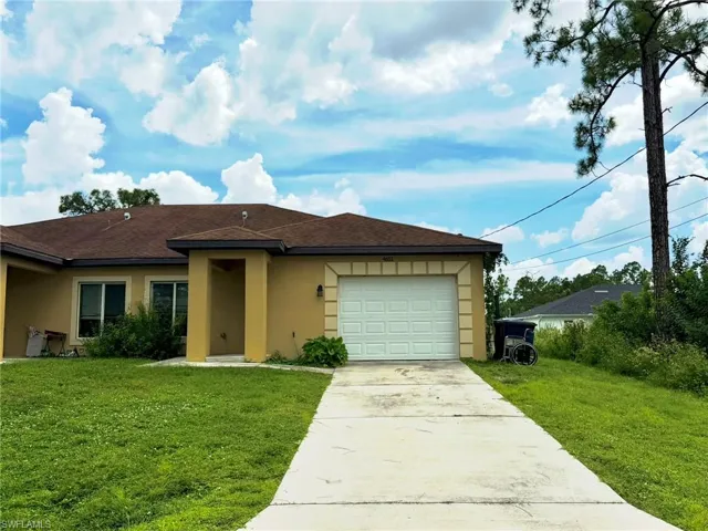 Tan exterior with a brown shingle roof, attached garage, concrete driveway, and front lawn