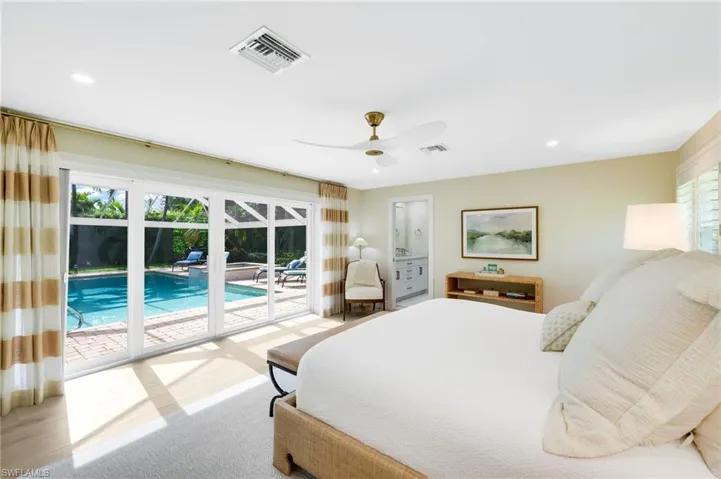 Spacious primary bedroom with pool view