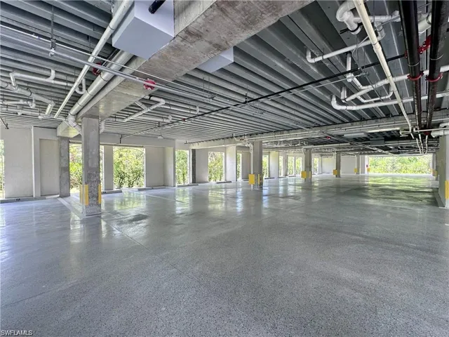 Spacious open-air parking structure featuring an exposed concrete ceiling, polished concrete flooring, and multiple support columns