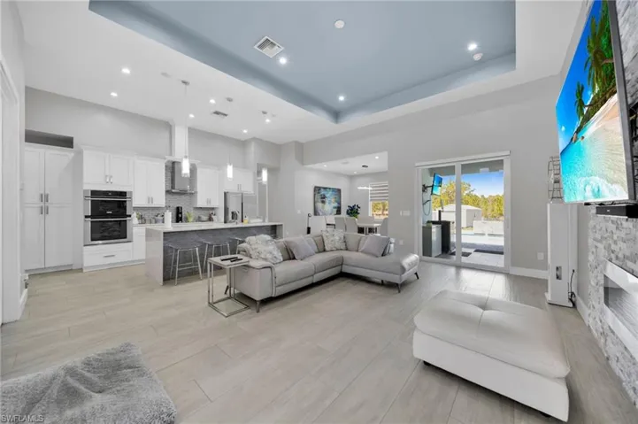 Living room featuring a high tray ceiling, wood tiled floors, and recessed lighting