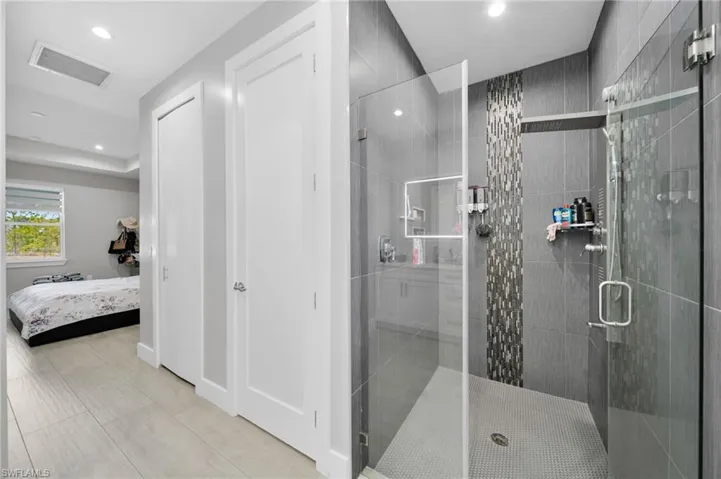 Ensuite bathroom featuring a stall shower, recessed lighting, and a closet