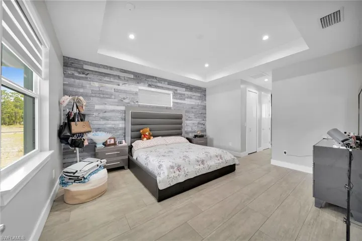 Bedroom with an accent wall, recessed lighting, and light wood-style flooring