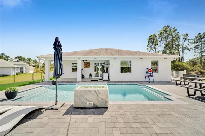 Rear view of property featuring a patio area, stucco siding, and an in-ground hot tub