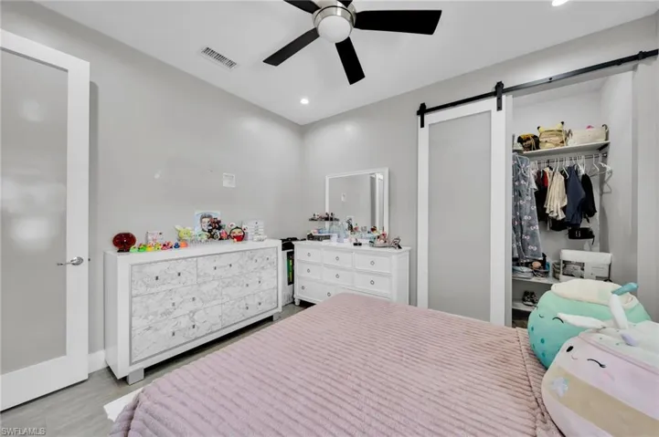 Bedroom with a barn door, a ceiling fan, recessed lighting, and a closet