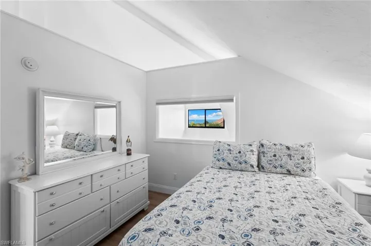 Bedroom with vaulted ceiling and dark wood-type flooring