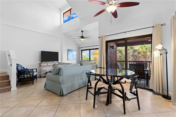 Living room with a high ceiling, ceiling fan, light tile patterned floors, and stairs