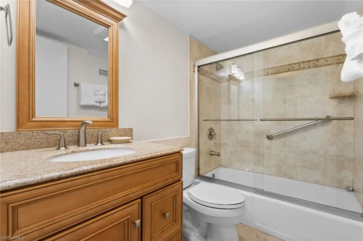 Full bath featuring shower / bath combination with glass door and vanity