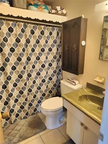 Full bath with light tile patterned flooring, vanity, and a shower with shower curtain