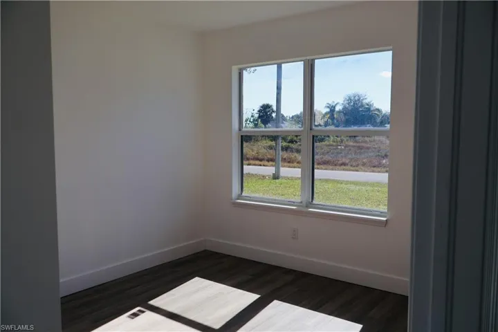 Spare room featuring baseboards and dark wood-type flooring