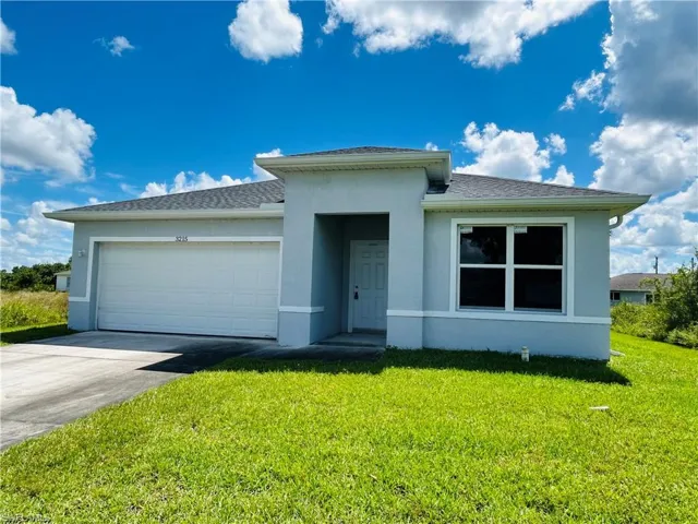 View of front of house featuring stucco siding, concrete driveway, and a front yard