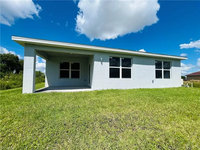 Back of house with stucco siding, a patio, and a yard